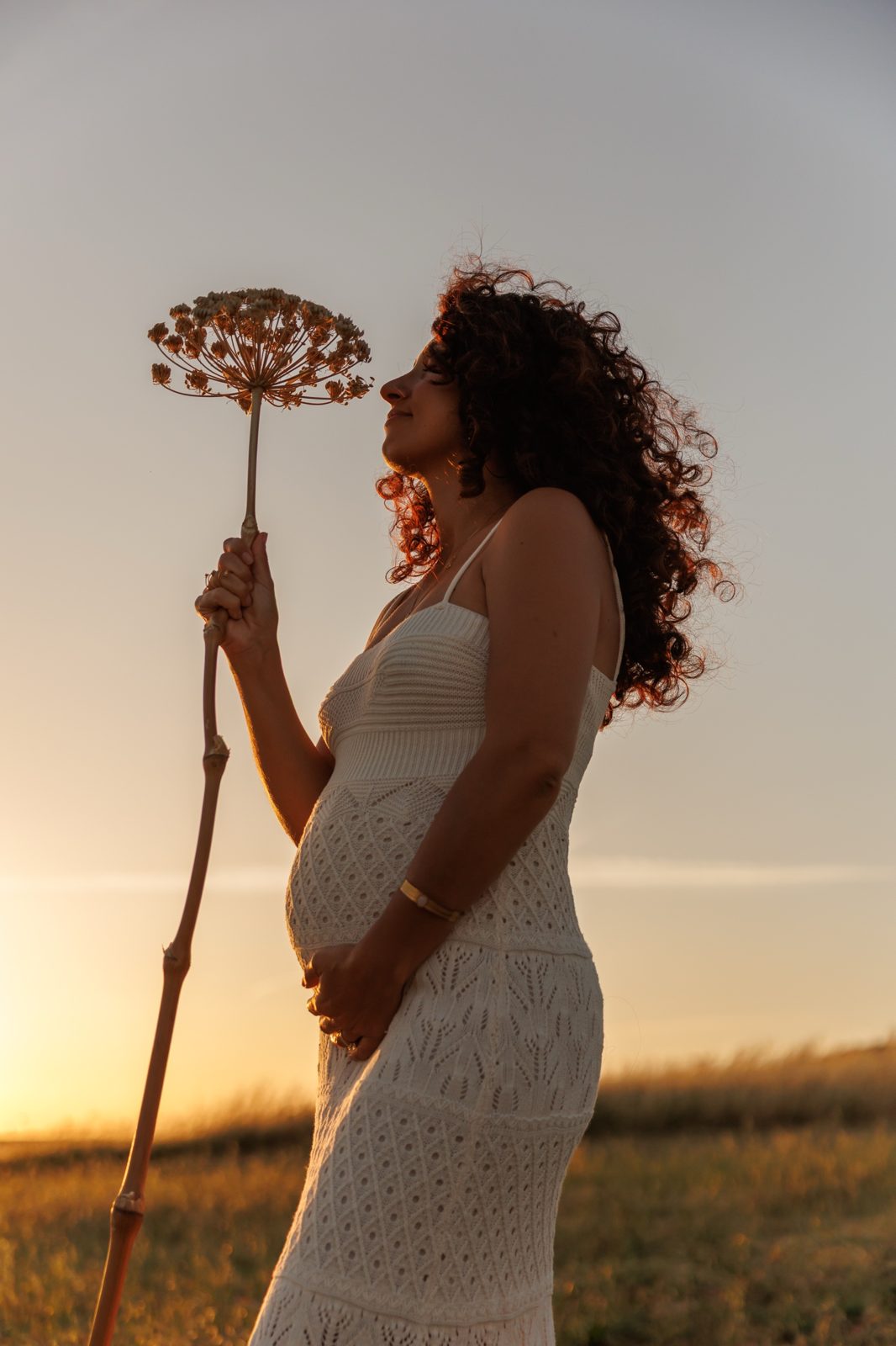 Claudia de profil au coucher du soleil, une grande fleur séchée à la main