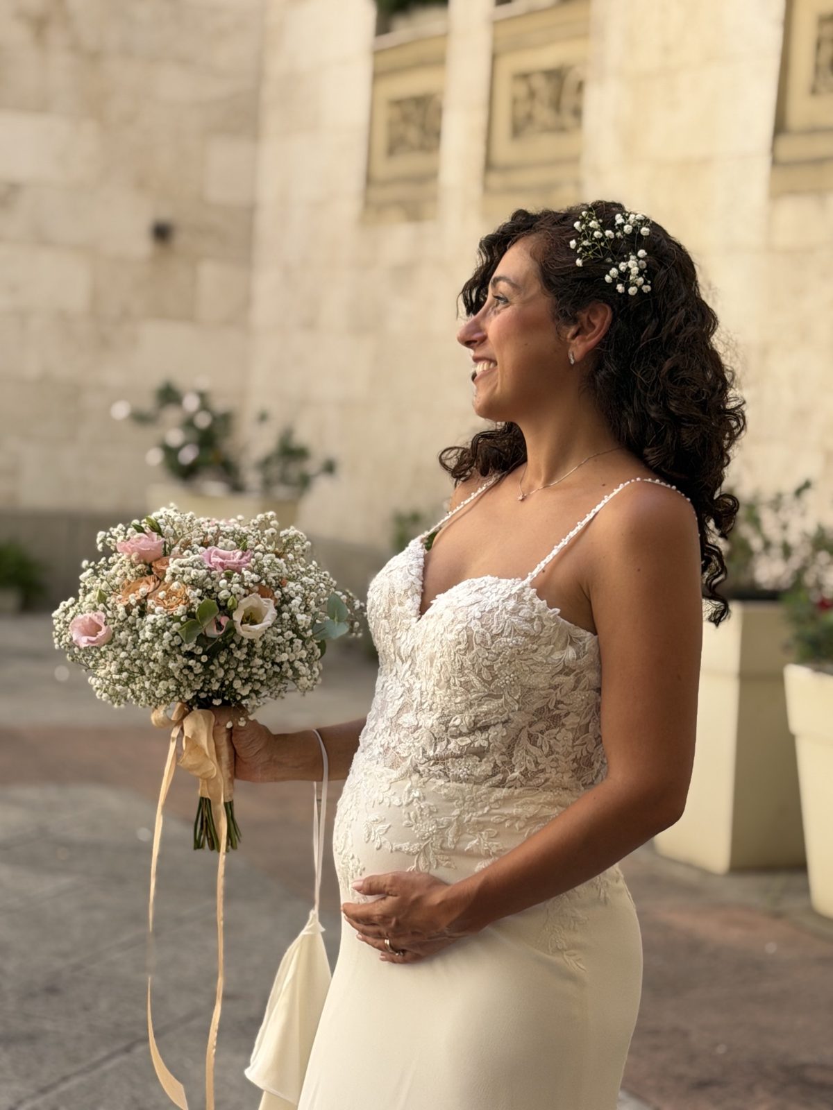 Claudia en robe de mariée, enceinte, son bouquet à la main